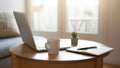 Open laptop on round table beside notebook and mug in bright morning light. Royalty Free Stock Photo