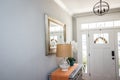 An open large and wide interior front door hallway foyer with transom, hanging light fixture, coastal colors and entry