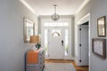 An open large and wide interior front door hallway foyer with transom, hanging light fixture, coastal colors and entry