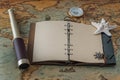 Open leather book with blank pages for writing text or a logo, a spyglass, a starfish and a brass compass lie on a vintage map Royalty Free Stock Photo