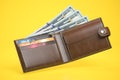 Open leather wallet with dollars and credit cards on yellow background