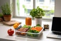 open lunchbox revealing a healthy meal, placed beside a notebook on a desk Royalty Free Stock Photo