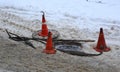 An open manhole on a snow-covered road is fenced with restrictive cones