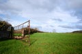 Open metal gate in field in countryside with clouds against blue sky Royalty Free Stock Photo