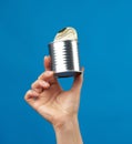 Open metal round tin can in a female hand on a blue background Royalty Free Stock Photo