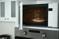 Open microwave oven with food on white shelf in kitchen Royalty Free Stock Photo