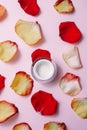 Open moisturizer on a pink pastel background among red, orange rose petals. The concept of skin care, anti-aging care Royalty Free Stock Photo