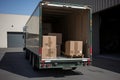 Open moving vehicle ready to be loaded with cardboard boxes with different items for transportation. Carton boxes on pallets in a Royalty Free Stock Photo