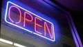 Open neon sign glowing in the dark. Vivid retro styled text at entrance on glass window. Colorful electric banner selective focus Royalty Free Stock Photo