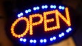 Open neon sign glowing in the dark. Vivid retro styled text at entrance on glass window. Colorful electric banner selective focus Royalty Free Stock Photo