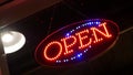 Open neon sign glowing in the dark. Vivid retro styled text at entrance on glass window. Colorful electric banner selective focus Royalty Free Stock Photo