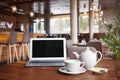 Open net-book and cup of tea with lemon on table in moder cafe / restaurant / bar interior. Royalty Free Stock Photo