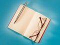 Open note, pen and eyeglasses on blue paper top view Royalty Free Stock Photo