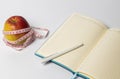 Open notebook with an apple and a centimeter on the table. Copy space Royalty Free Stock Photo