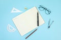 Open notebook, ballpen, pencil, sharpener, rulers, and eyeglasses isolated on a blue surface Royalty Free Stock Photo