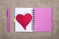 Open notebook with ballpoint pen and red heart of wool on a burlap background Royalty Free Stock Photo