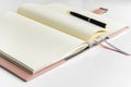 An open notebook with yellow sheets lies on a white table, next to a pen. Royalty Free Stock Photo