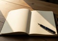 An open notebook with blank, cream-colored pages rests on a wooden table. Sunlight Royalty Free Stock Photo