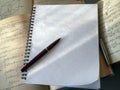 An open notebook with a blank page and a fountain pen on top. The notebook lies on top of open books. Close-up. Royalty Free Stock Photo