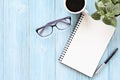 Open notebook with blank pages, coffee cup and eyeglasses on wooden desk table, top view or flat lay with copy space Royalty Free Stock Photo