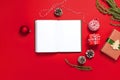 Open notebook with blank pages, gift boxes, fir branches, ball on red background flat lay top view. Christmas planning concept Hol Royalty Free Stock Photo