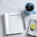 Open notebook with blank to-do list, silver pen, fresh lime slice, and steaming coffee cup on marble surface, creating a Royalty Free Stock Photo