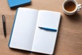 Open notebook with blue pen and coffee cup on a wooden desk providing a workspace scene view Royalty Free Stock Photo