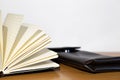 Open notebook and brown case on a wooden table