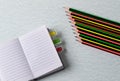 Open notebook with colored bookmarks and pencils on a table.