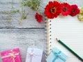 open notebook with flower ,gift boxes, pencil on wood background Royalty Free Stock Photo