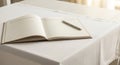 Open notebook with lined pages and a pen resting on a white tablecloth Royalty Free Stock Photo