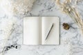 Open notebook with metal pen on marble surface Royalty Free Stock Photo