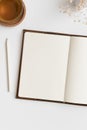 Open notebook mockup with a cup of tea and gypsophila on a white table Royalty Free Stock Photo