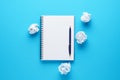 Open notebook, pen and crumpled paper balls on blue background. Royalty Free Stock Photo