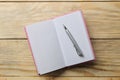 Open notebook and pen on the natural wooden table. top view. office tools Royalty Free Stock Photo