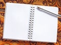 Open notebook with pen on oriental fabric