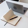 Open notebook with pen resting beside a laptop on desk Royalty Free Stock Photo