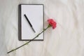 Open Notebook and a pen with Violet carnation flower on a white tulle fabric Royalty Free Stock Photo