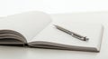 Open Notebook with Pen on White Surface Royalty Free Stock Photo