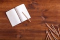 Open notebook with pencils on brown wooden desk, writer work desk concept, empty paper blank office school notepad for writing