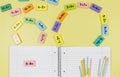 Open notebook, pencils and mathematical examples on yellow background. Back to school, fun learning of counting numbers for kids