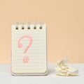 An open notebook with a question mark drawn in red pencil next to a crumpled piece of paper Royalty Free Stock Photo