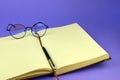 Open notebook and round glasses. Stylish glasses, notepad and pen, close-up. Blank pages of a notebook and glasses Royalty Free Stock Photo