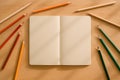 Open Notebook Surrounded by Colored Pencils on Brown Background Royalty Free Stock Photo