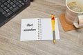 Open notebook with Text `Start Somewhere` and a cup of coffee on wooden background.