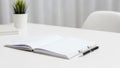 Open notebook on a white desk accompanied by a black pen with silver accents Royalty Free Stock Photo