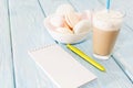 Open notebook, white mug with coffee, marshmallows.