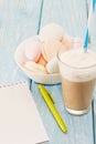 Open notebook, white mug with coffee, marshmallows.