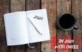 Open notebook on wooden background. White pen. A list or plan for 2020. Black cup with tea or coffee Royalty Free Stock Photo