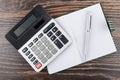 Open notepad, ballpoint pen and electronic calculator on table